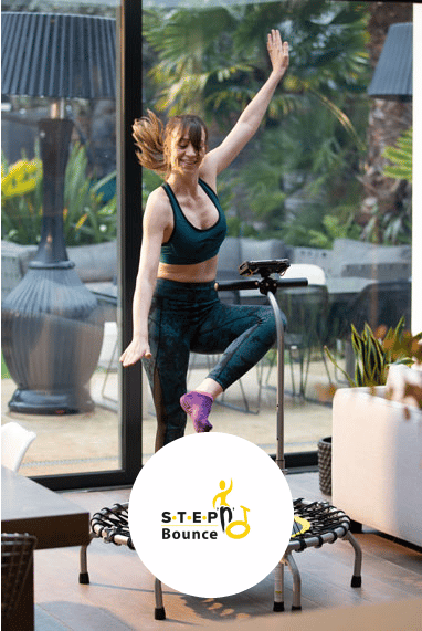 person smiling while bouncing on their rebounder to the Step and Bounce routine.
